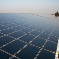 Große Photovoltaikanlage auf einem Flachdach bei klarem Himmel, Blick über die Modulflächen.